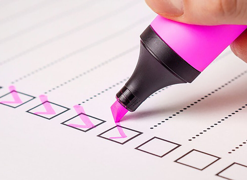 A list of checklist boxes being ticked off with a pink highlighter.