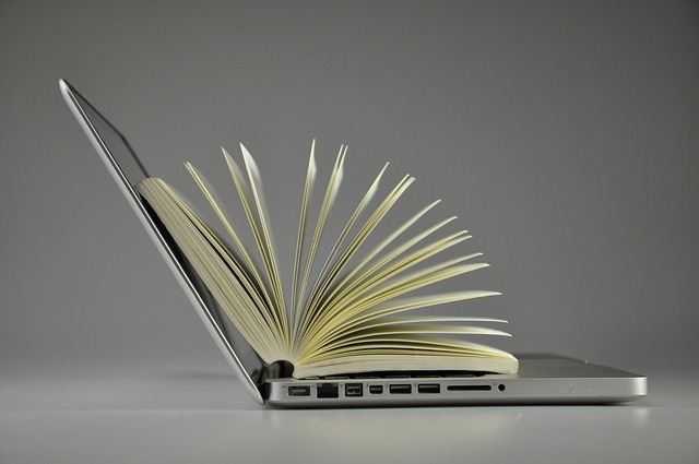 A book opened on top of an open laptop.