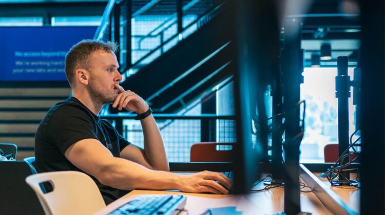 A person sat at a computer cluster computer, they are looking at the screen