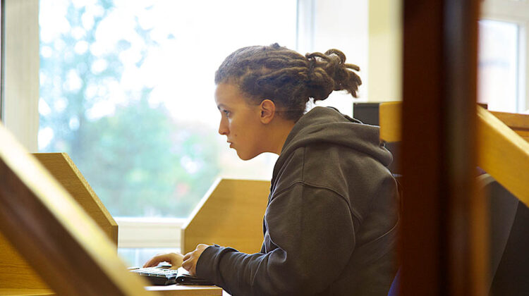 Student looking at screen with hand on keyboard.