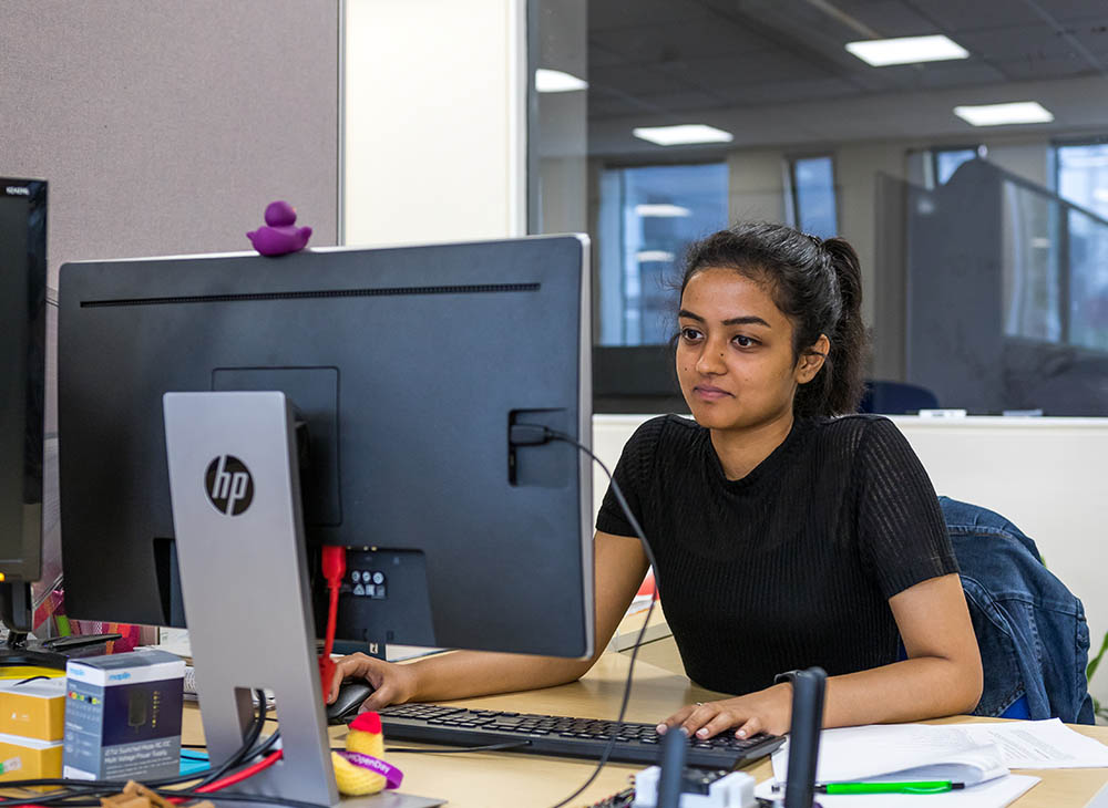 Student looking at computer with one hand on the mouse, the other on the keyboard.