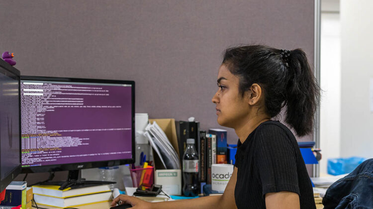 Student looking at a computer with one hand on mouse and other hand on keyboard