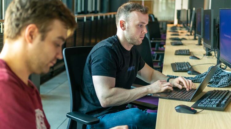 Two students working on a desk on individual PC's in MECD