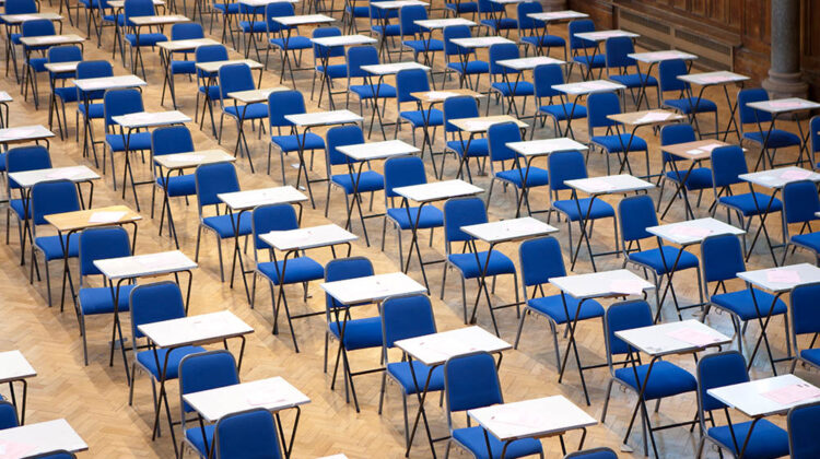 Empty exam hall full of chairs and desks.