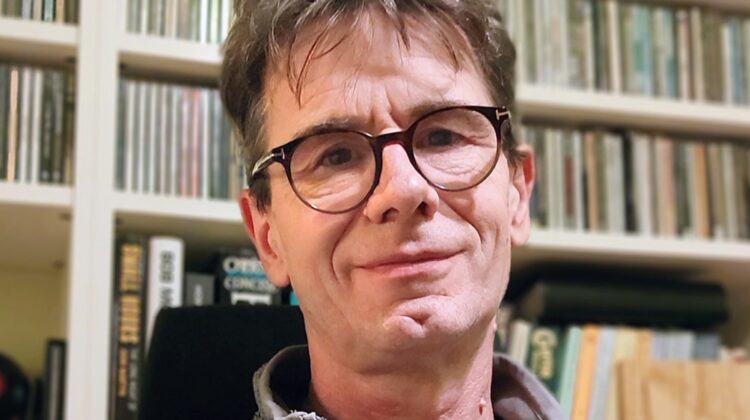 Joz Sly sat in front of a book case