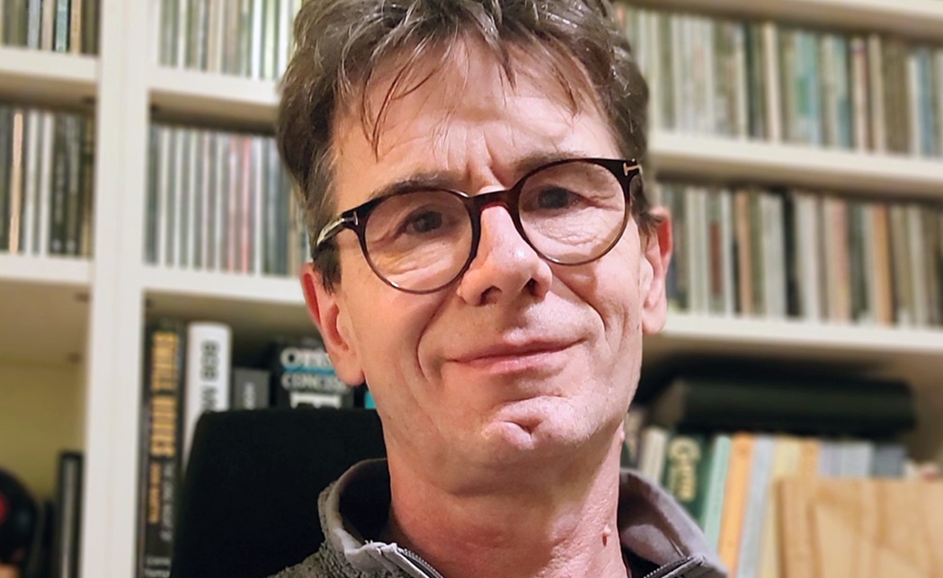 Joz Sly sat in front of a book case