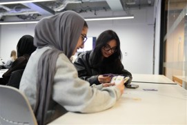 Two students who are the undergraduate developers of the cards, playing the game during the PASS leaders EDIA session.
